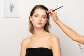 Vista frontal de un maquillador aplicando polvos faciales para un modelo femenino