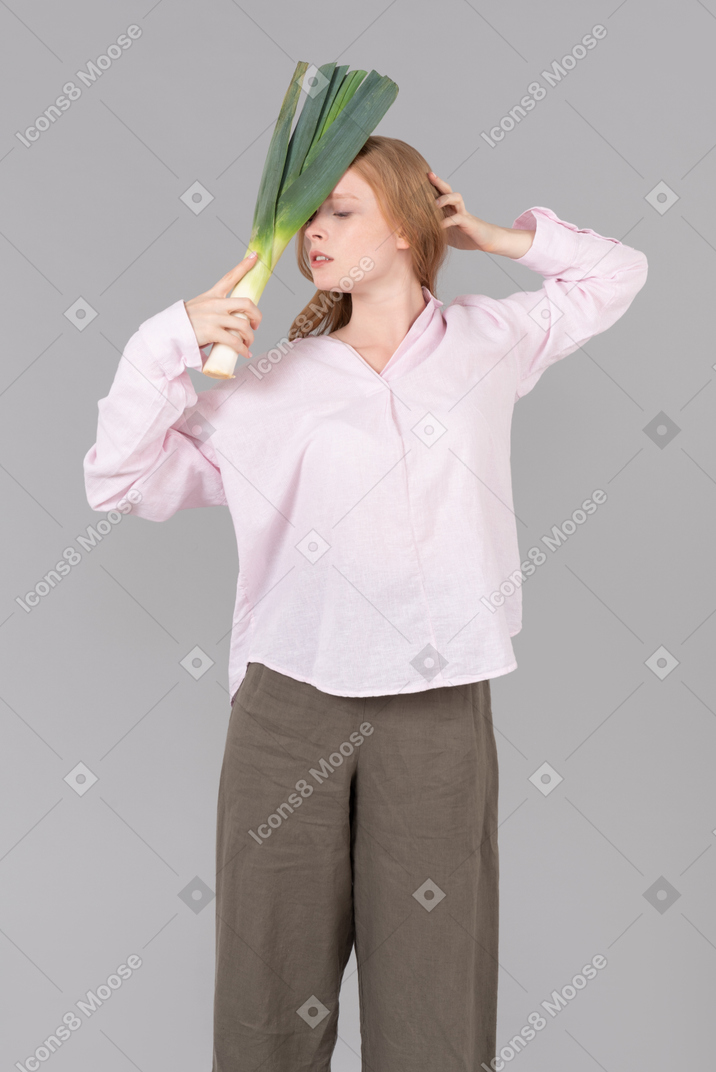 Young woman holding leek onion close to herself