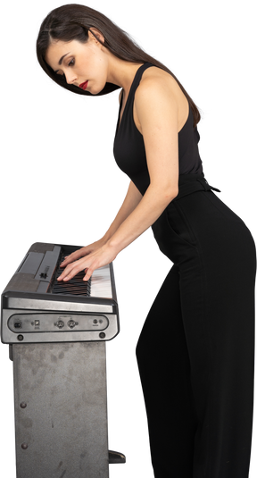 Vista laterale di una giovane donna in abito nero a suonare il pianoforte