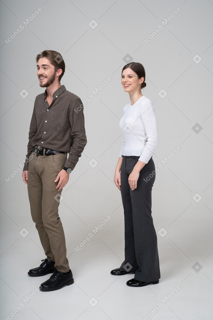 笑对年轻的夫妇，在办公室服装中的四分之三的视图