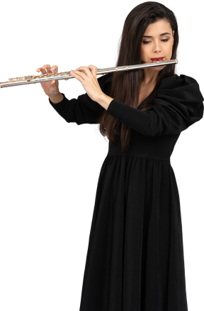 Vorderansicht einer ernsten jungen dame im schwarzen kleid, die flöte spielt