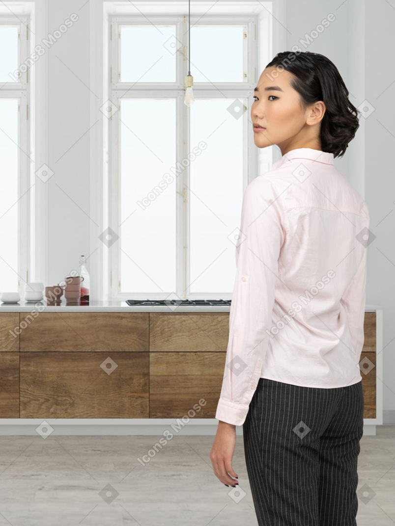 A woman in a pink shirt is standing in a kitchen