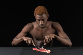 Vista frontal de un joven afro cortando carne