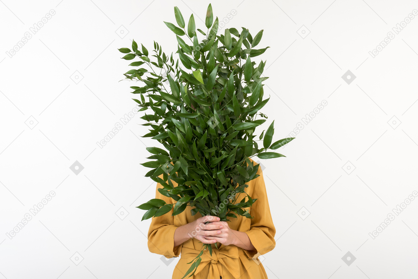 Young woman closing face with bouquet of green branches
