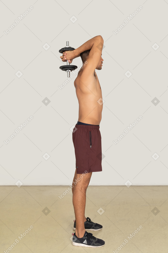 Side view of muscular man holding dumbbell behind his head