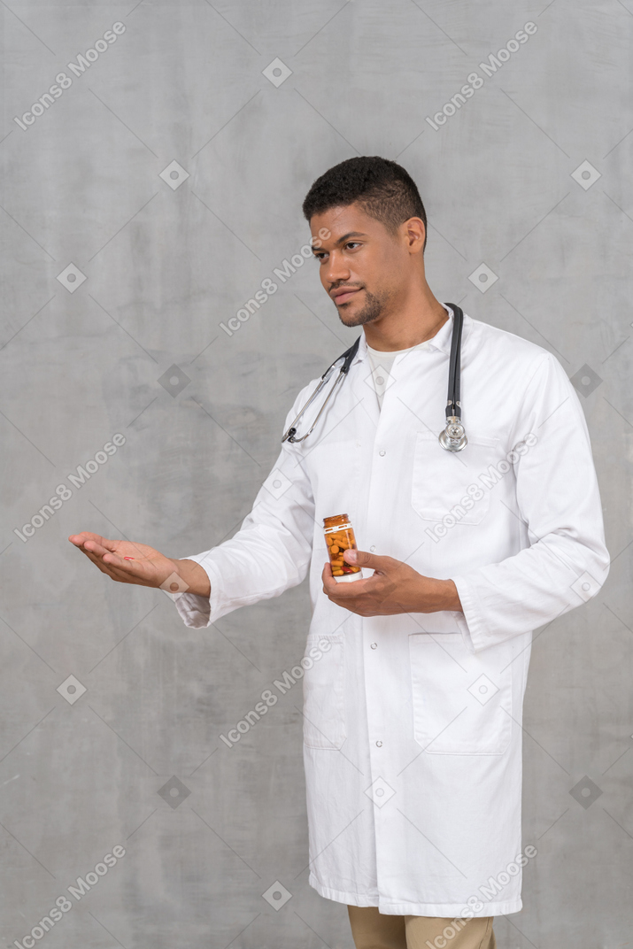 Young male doctor offering a pill