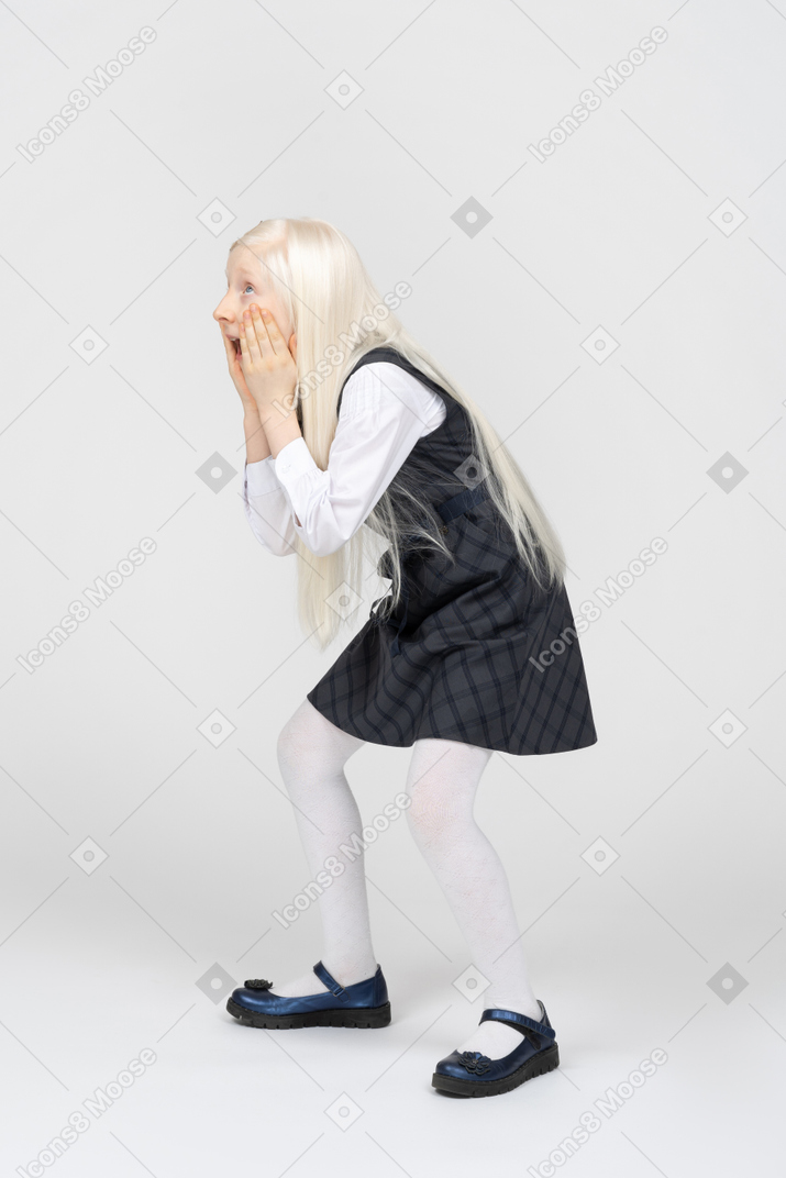 Schoolgirl holding her face and looking amazed