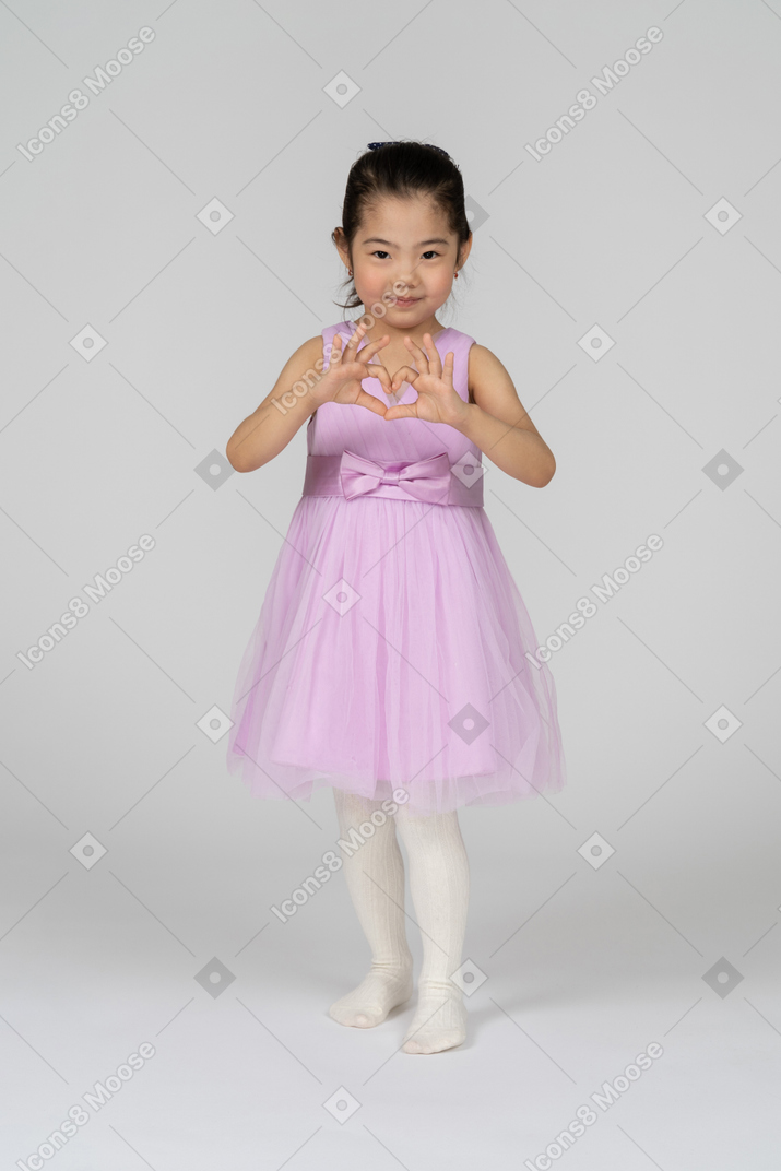 Portrait of a cute little girl making a heart with her hands
