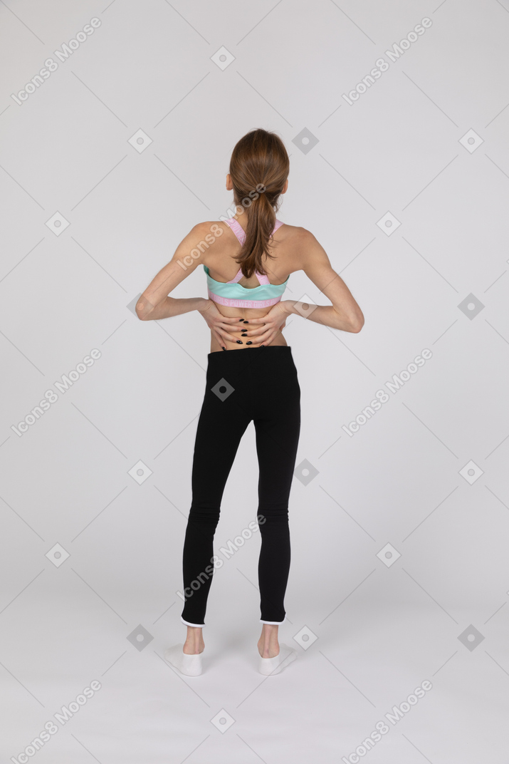 Девушка-подросток в спортивной одежде страдает от болей в спине