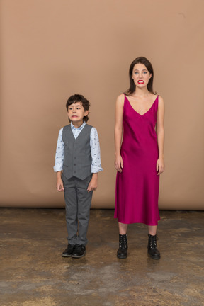 Front view of a grinning boy and woman in red dress