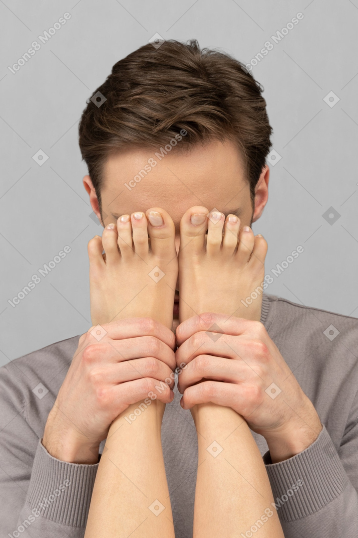 Homem segurando as pernas femininas na frente de seu rosto