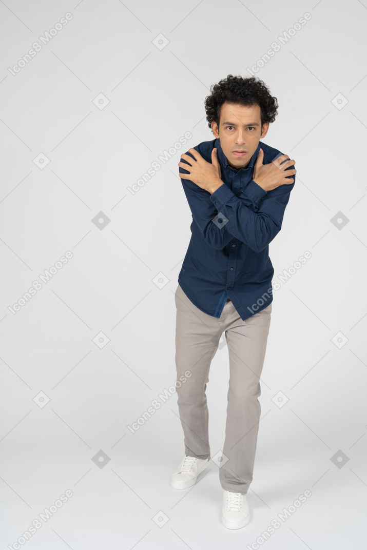 Front view of a man in casual clothes hugging himself and looking at camera