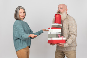 Aged man giving gifts to an elegant mature woman