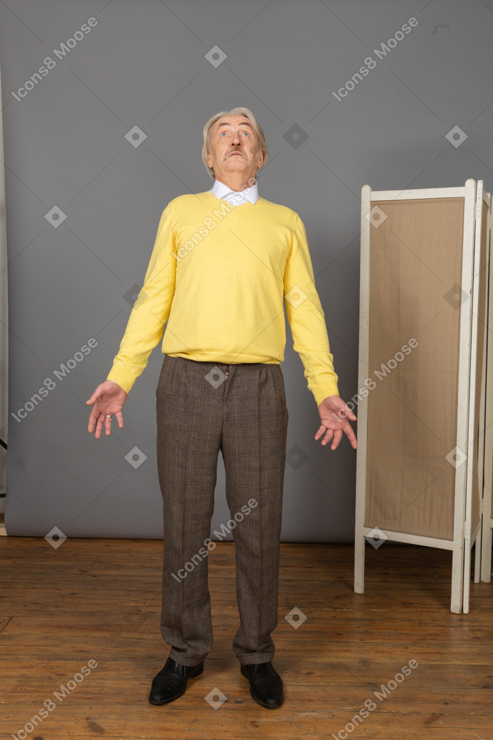 Front view of a questioning old man looking up while outspreading hands