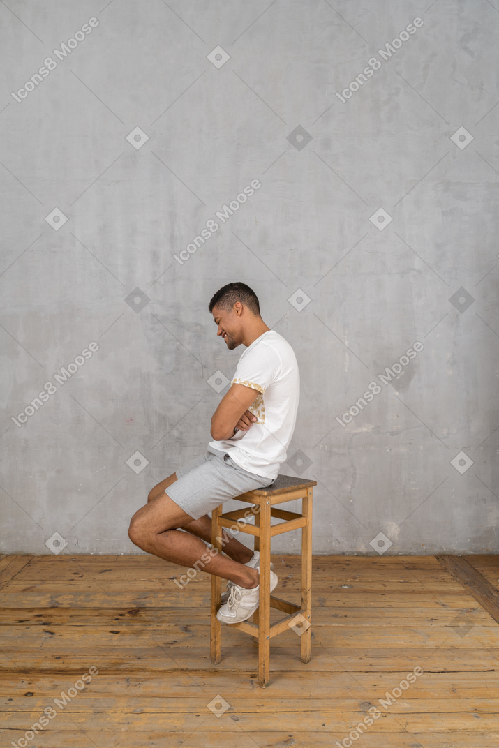 Vue latérale du jeune homme assis et riant