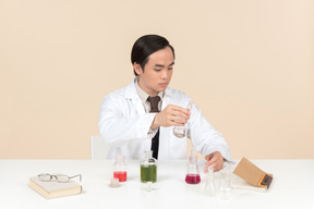 An asian scientist in a white coat working on a chemical experiment