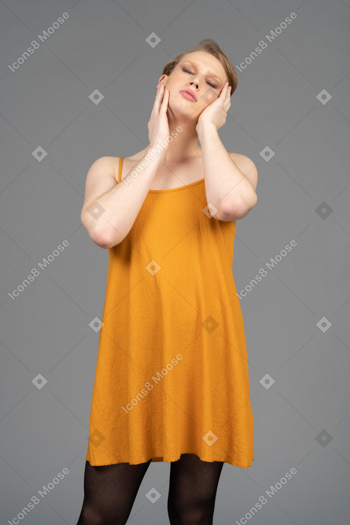 Persona joven no binaria sosteniendo su cara con ambas manos