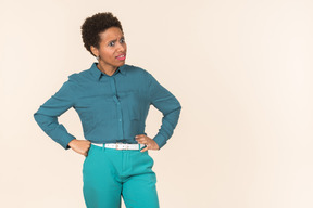 Негритянка с короткой стрижкой, одетая во все синие, стоящая на простом пастельном фоне, выглядящая эмоционально