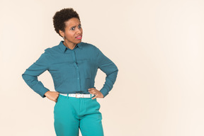 Black woman with a short haircut, wearing all blue, standing against a plain pastel background, looking emotional