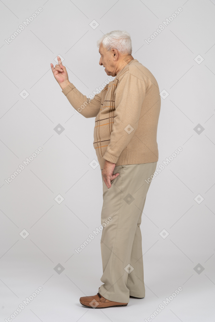 Vista lateral de um velho em roupas casuais fazendo gesto de rock