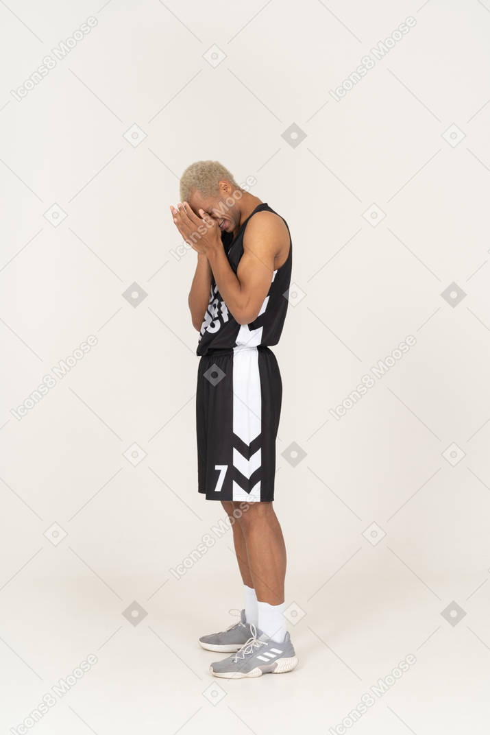 Side view of a withdrawn young male basketball player touching face