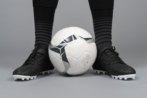 Close-up das pernas de um jogador de futebol segurando uma bola