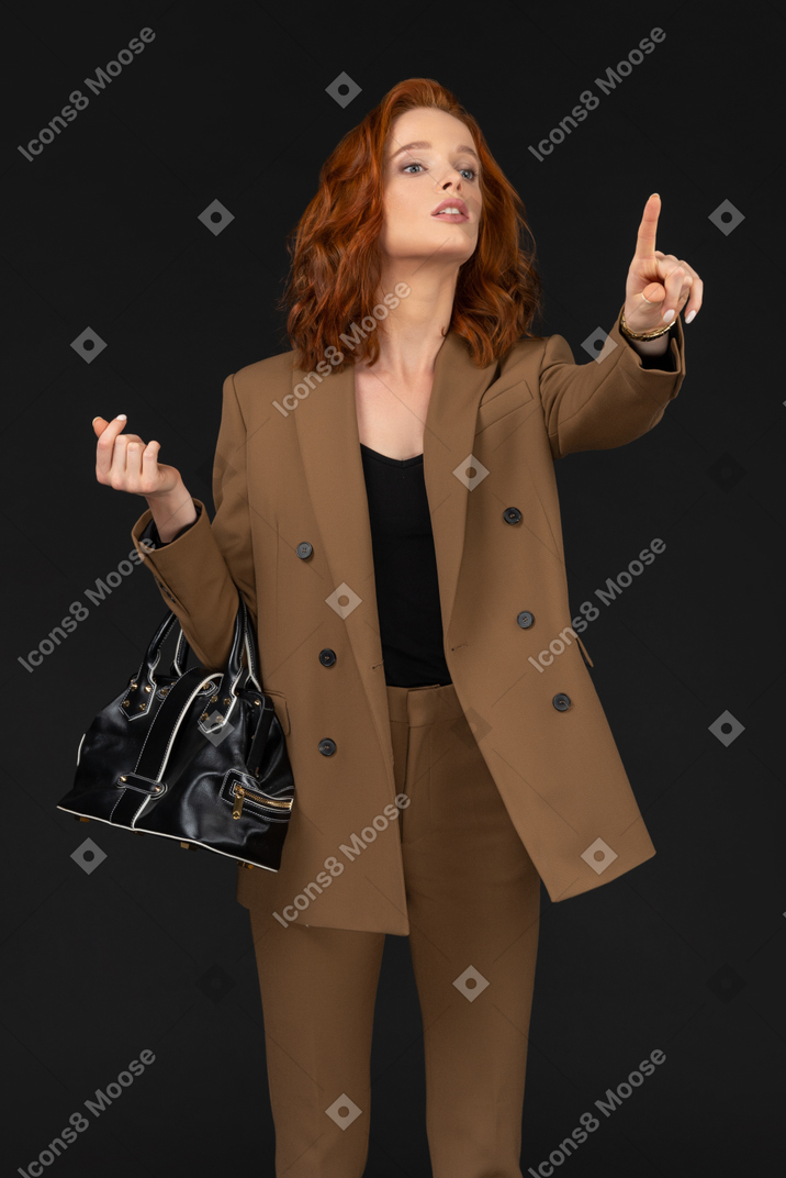 Young businesswoman with handbag gesturing