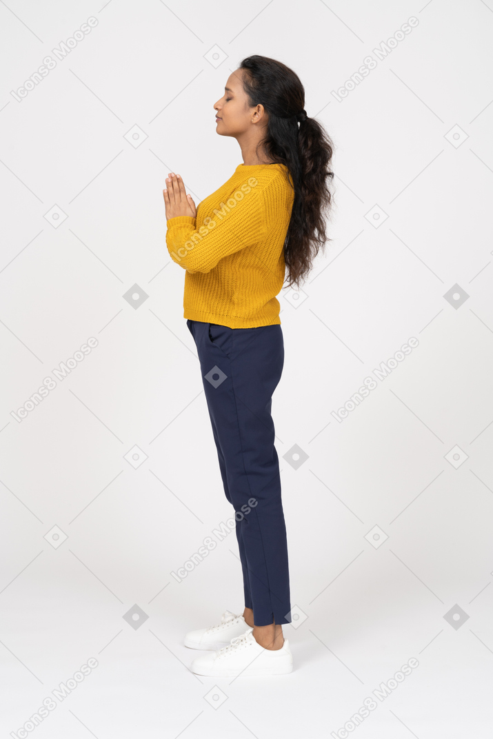 一个穿着休闲服的女孩做祈祷手势的侧视图