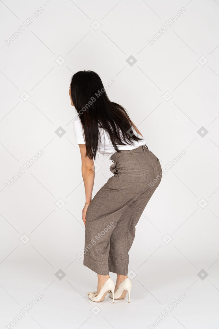 一位年轻的女士，身着马裤和向前倾斜的t恤的四分之三后视图