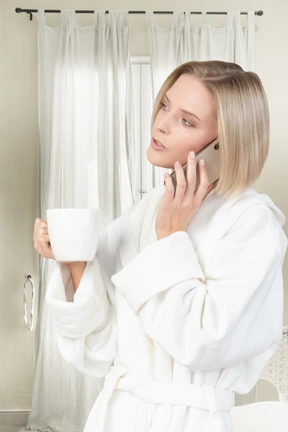 A woman in a bathrobe talking on a cell phone