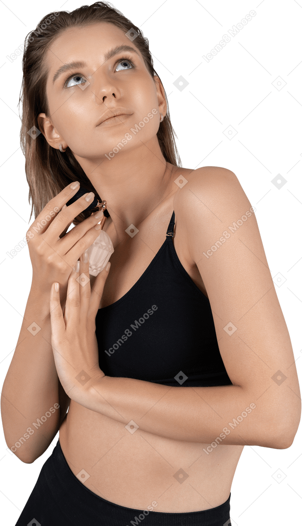 Vista di tre quarti di una giovane donna con in mano una bottiglia di profumo