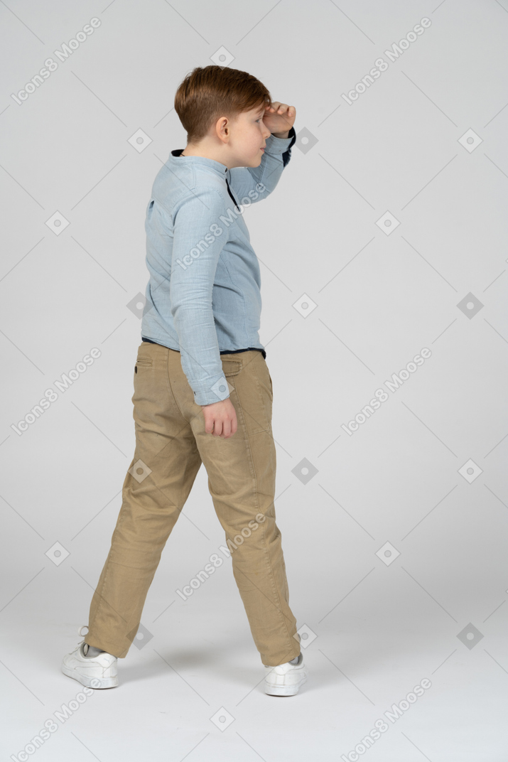Boy turning to the right and looking for something