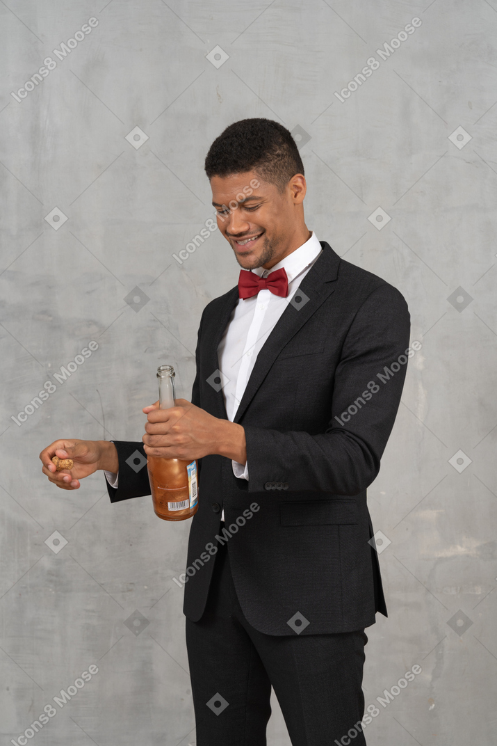 Hombre sosteniendo una botella de champán y sonriendo ampliamente