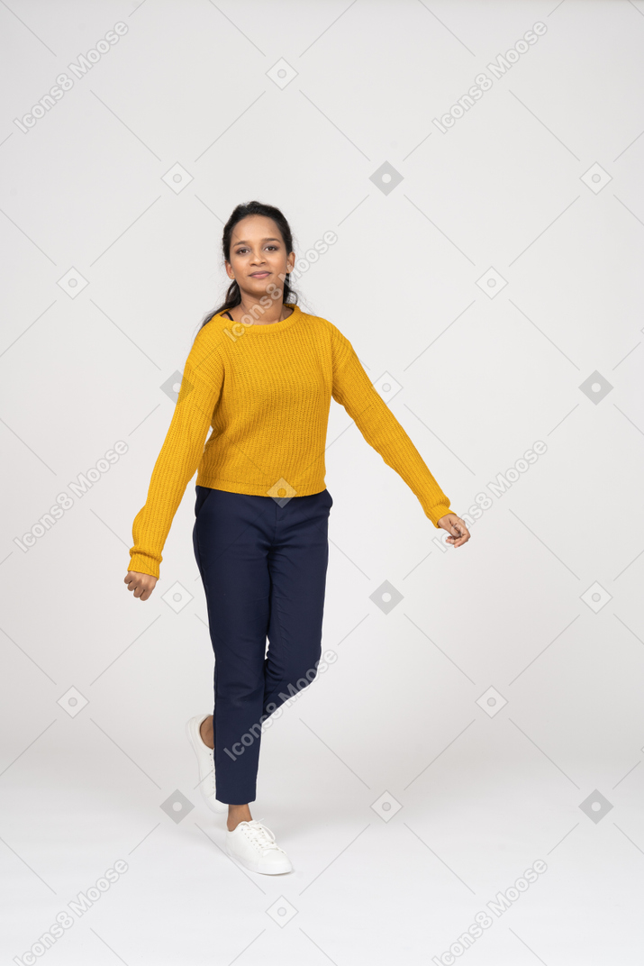 Front view of a girl in casual clothes walking forward with outstretched arms