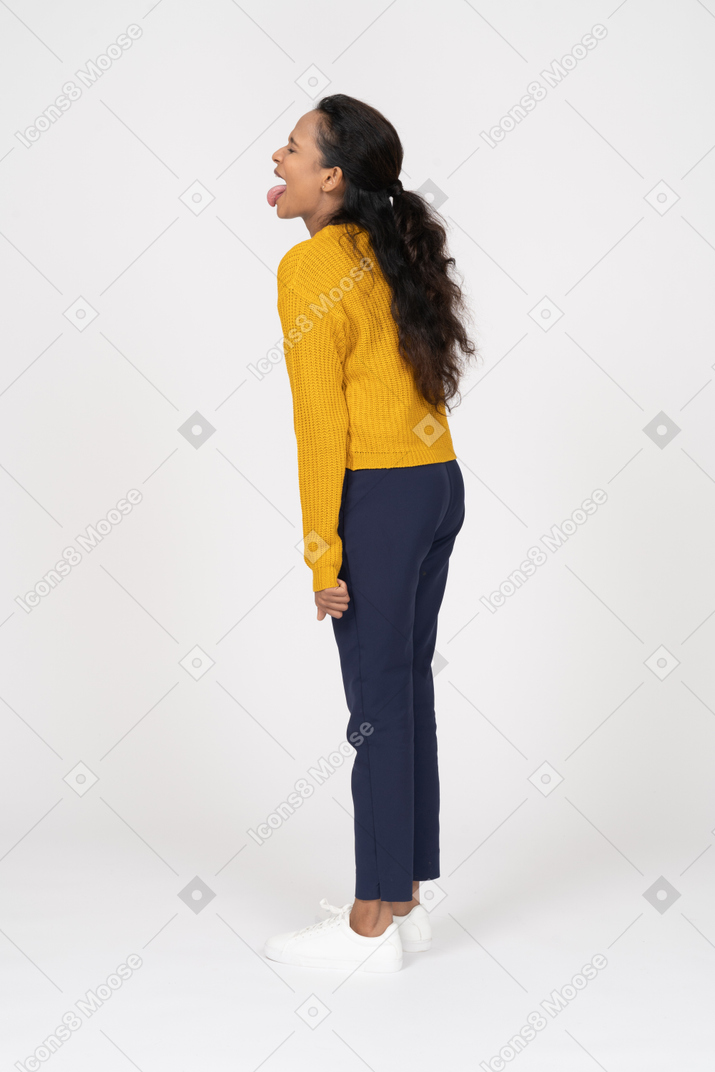 Side view of a happy girl in casual clothes showing tongue