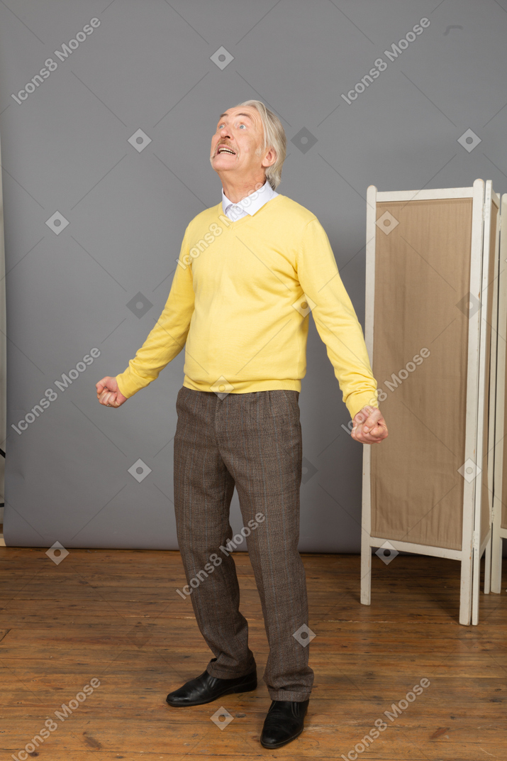 Three-quarter view of a screaming old man outspreading hands while looking up