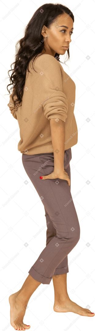 Vista lateral de una mujer joven de piel oscura poniendo la mano en la cadera