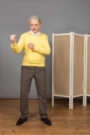 Vista frontal de un anciano apretando los puños listo para defender