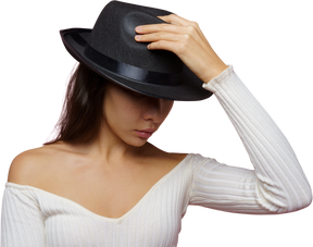 Vista frontal de una misteriosa dama escondiendo su rostro y sosteniendo un sombrero negro