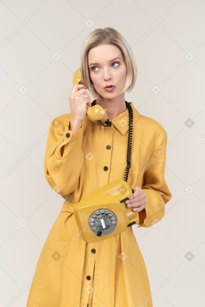 Cute young woman talking on retro phone