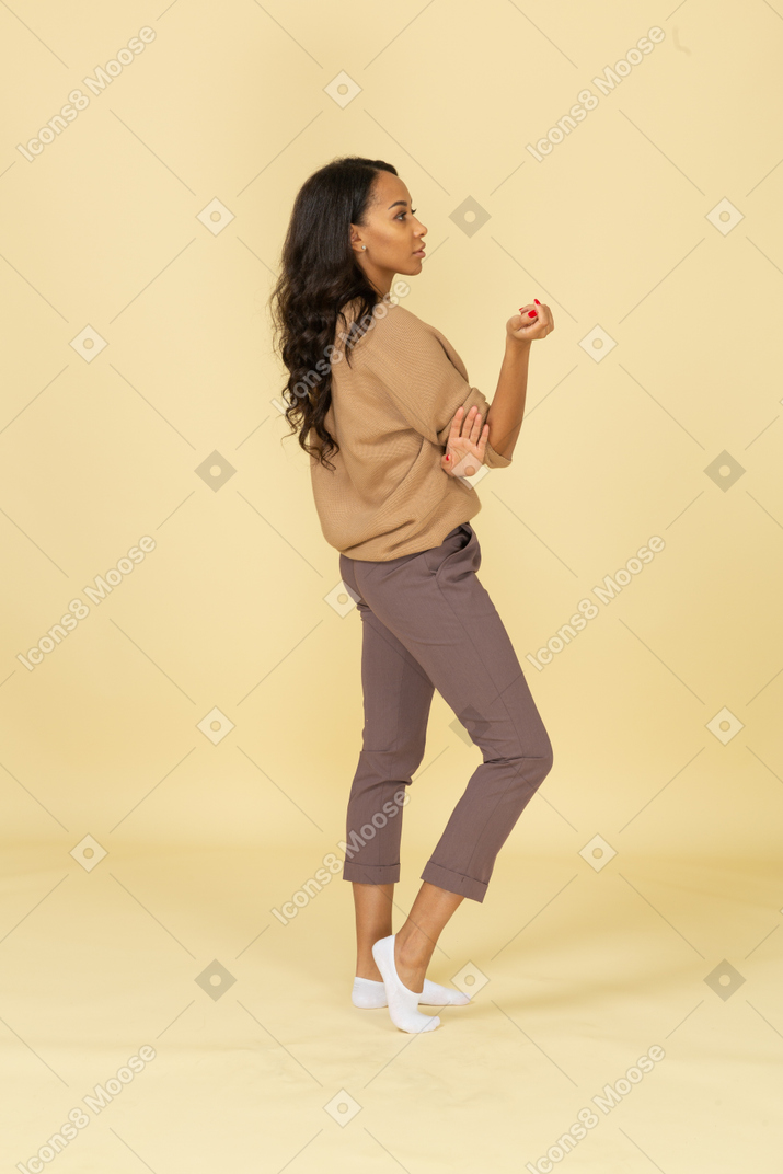 Side view of a dark-skinned questioning young female raising hand