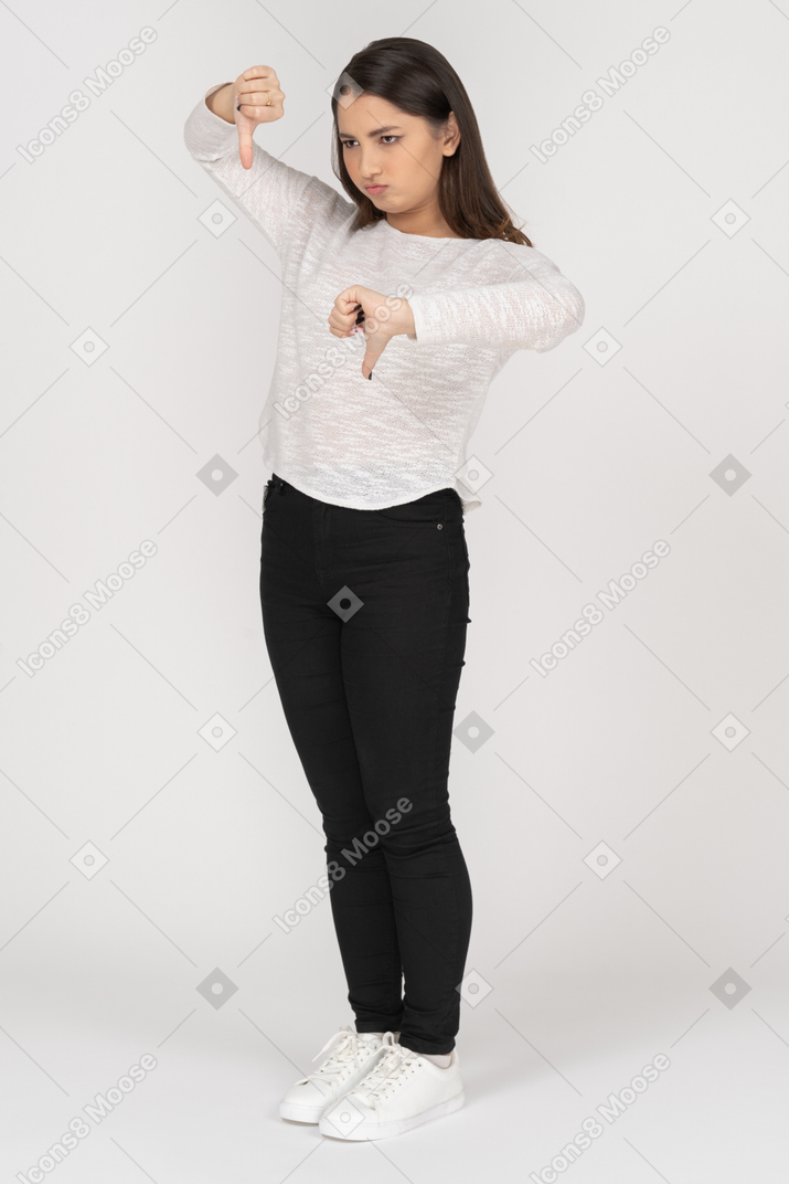 Three-quarter view of a young indian female in casual clothing showing thumbs down