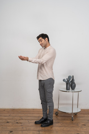 Vista lateral de um homem com roupas casuais em pé com as mãos estendidas