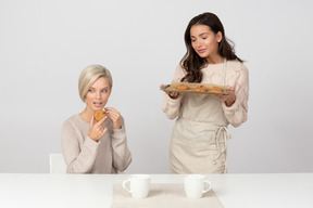 Mujer joven comiendo las galletas de su amiga