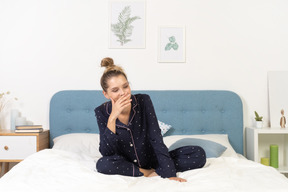 一个穿着睡衣的微笑年轻女子躺在床上的前视图