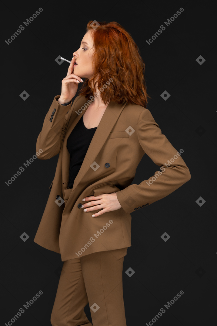 Side view of a young businesswoman smoking a cigarette