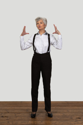 Front view of an old female in office clothes gesticulating actively standing in the room