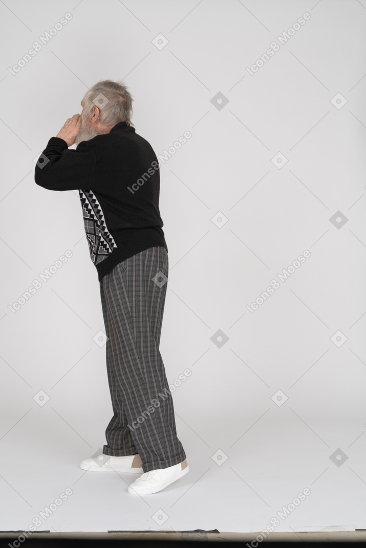 Side view of old man holding hand near mouth