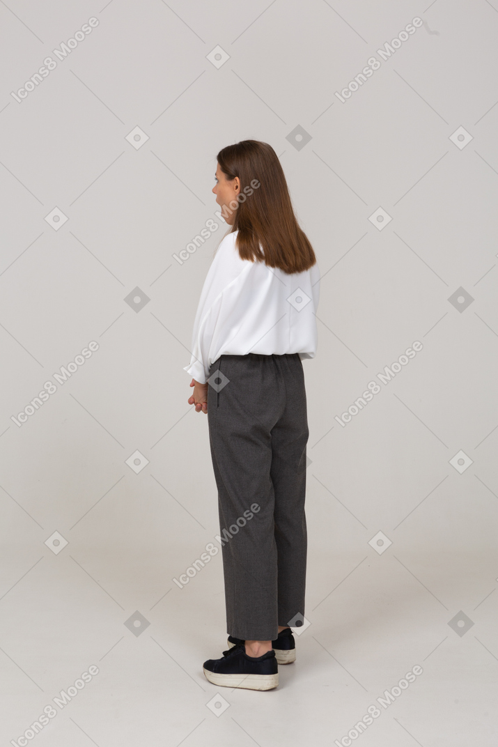 Three-quarter back view of a shocked young lady in office clothing holding hands together