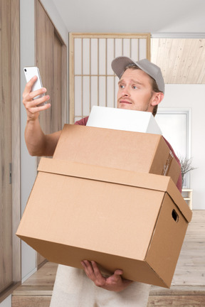 A man holding a cardboard box and a cell phone